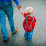 father walking little daughter to daycare, back to school